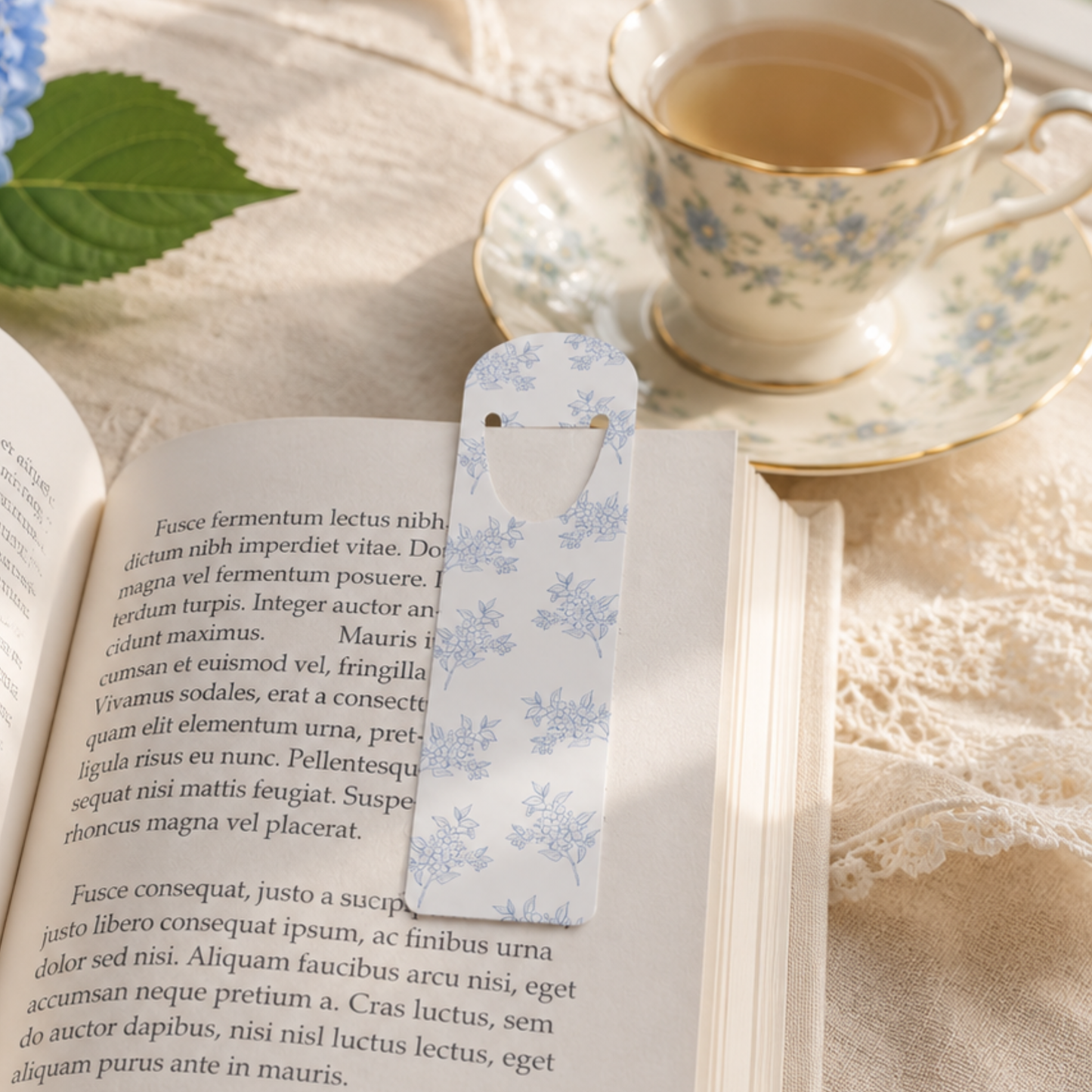Blue floral metal bookmark marking a page in an open book, elegant reading accessory for book lovers