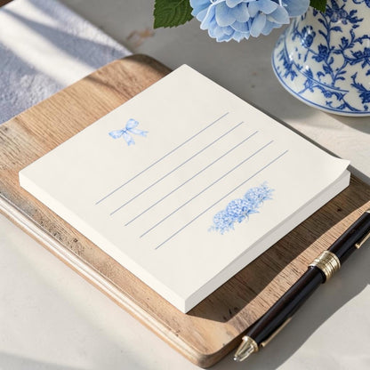 Blue bow and hydrangea sticky note pad displayed on a vintage-inspired writing desk with elegant stationery accessories
