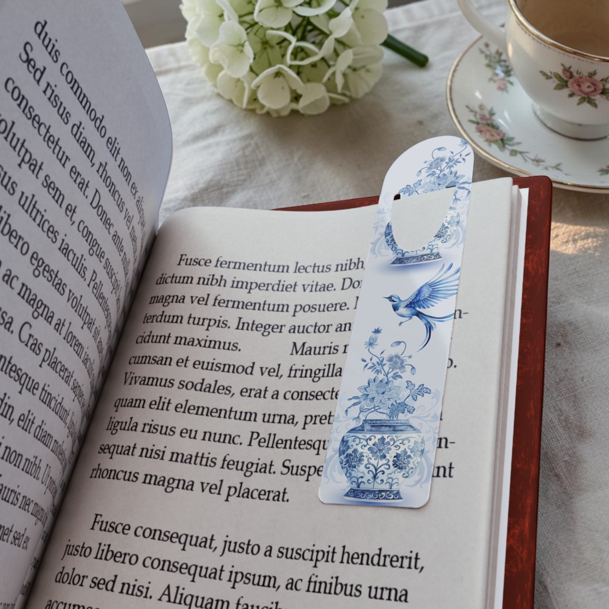 Blue chinoiserie metal bookmark placed inside an open book, elegant reading accessory for book lovers