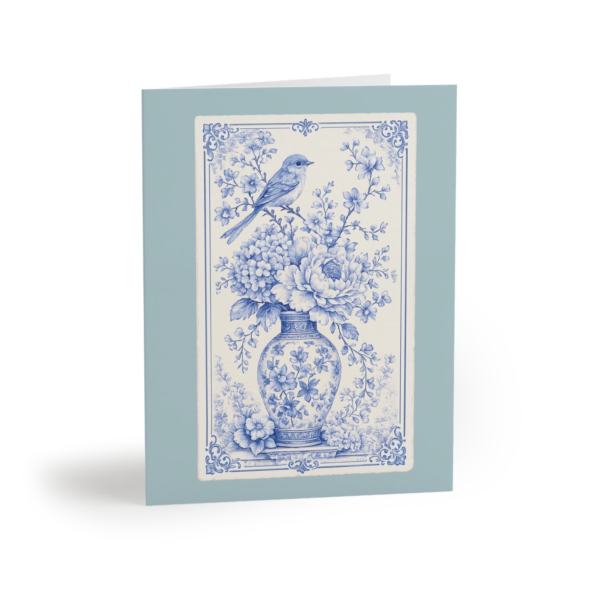 Blue chinoiserie floral greeting card featuring a vintage bird and porcelain vase illustration on a soft sea-glass blue folded card.