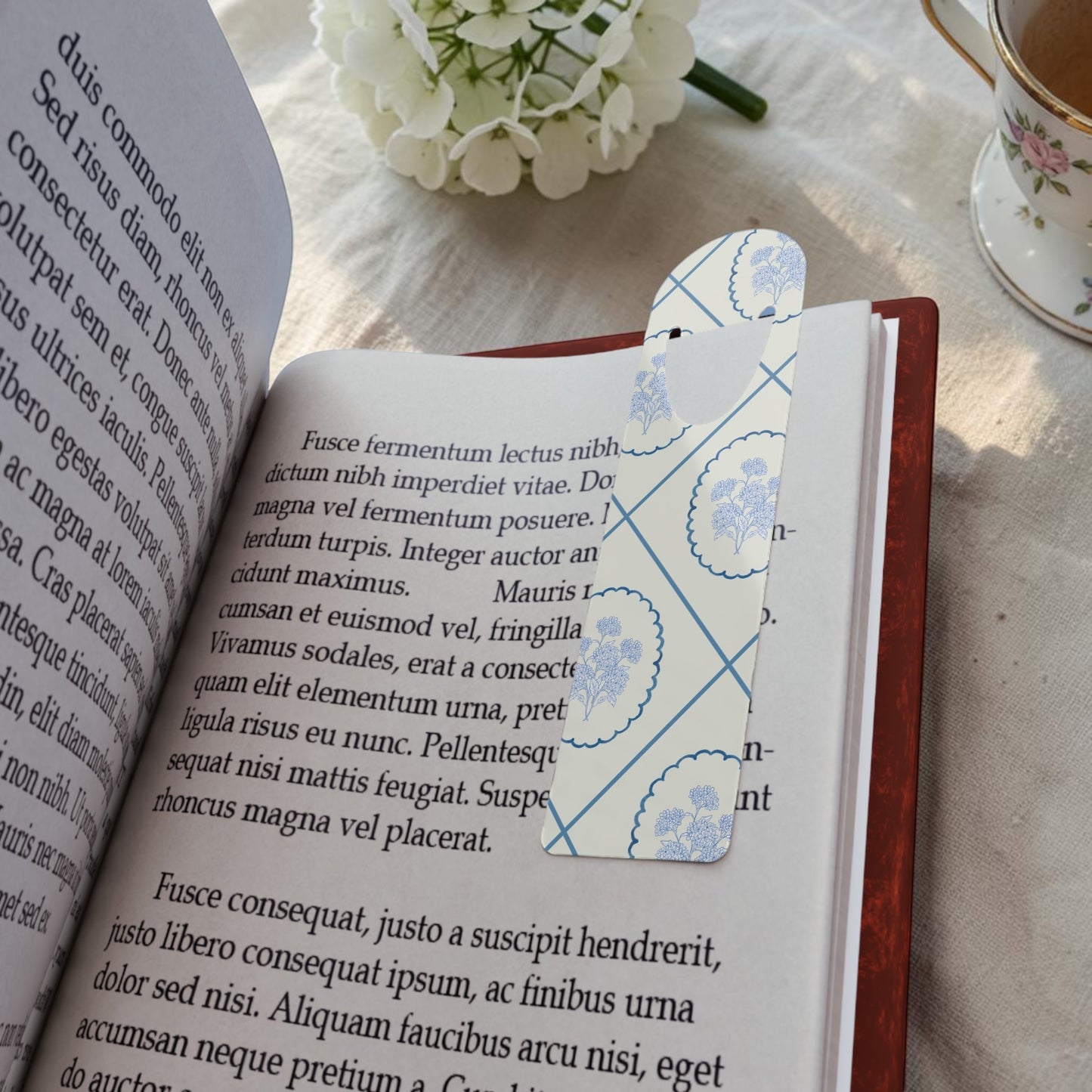 Blue Delft floral metal bookmark placed inside an open book with soft cottagecore styling
