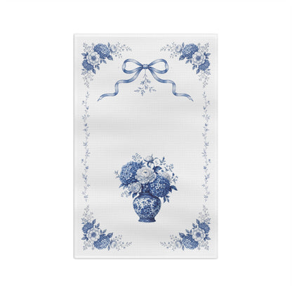 Front view of a blue Delft hydrangea microfiber tea towel with floral corners, ribbon detail, and a porcelain vase bouquet.
