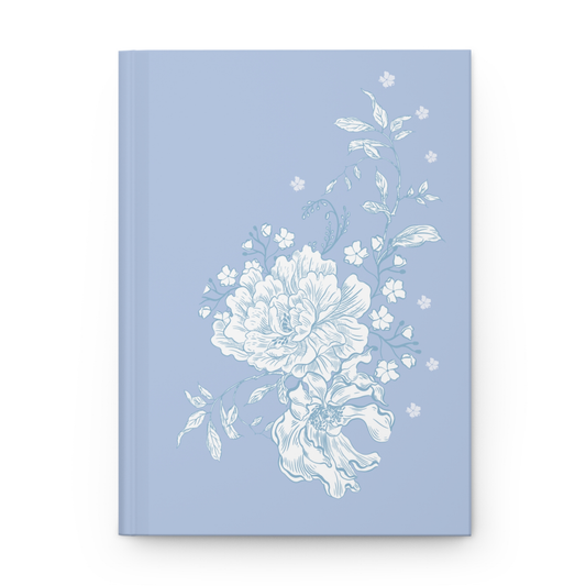 Blue floral hardcover journal with white peony design on matte powder blue cover, styled with soft fabric and flowers