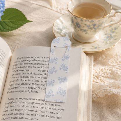 Blue floral metal bookmark marking a page in an open book, elegant reading accessory for book lovers