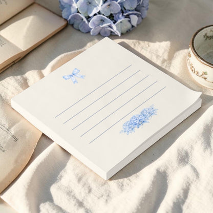 Blue hydrangea sticky notes styled on soft ivory fabric with floral accents in a cottagecore stationery setting