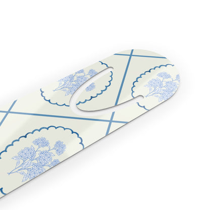Close-up angled view of a blue Delft floral metal bookmark featuring a delicate ceramic-inspired pattern