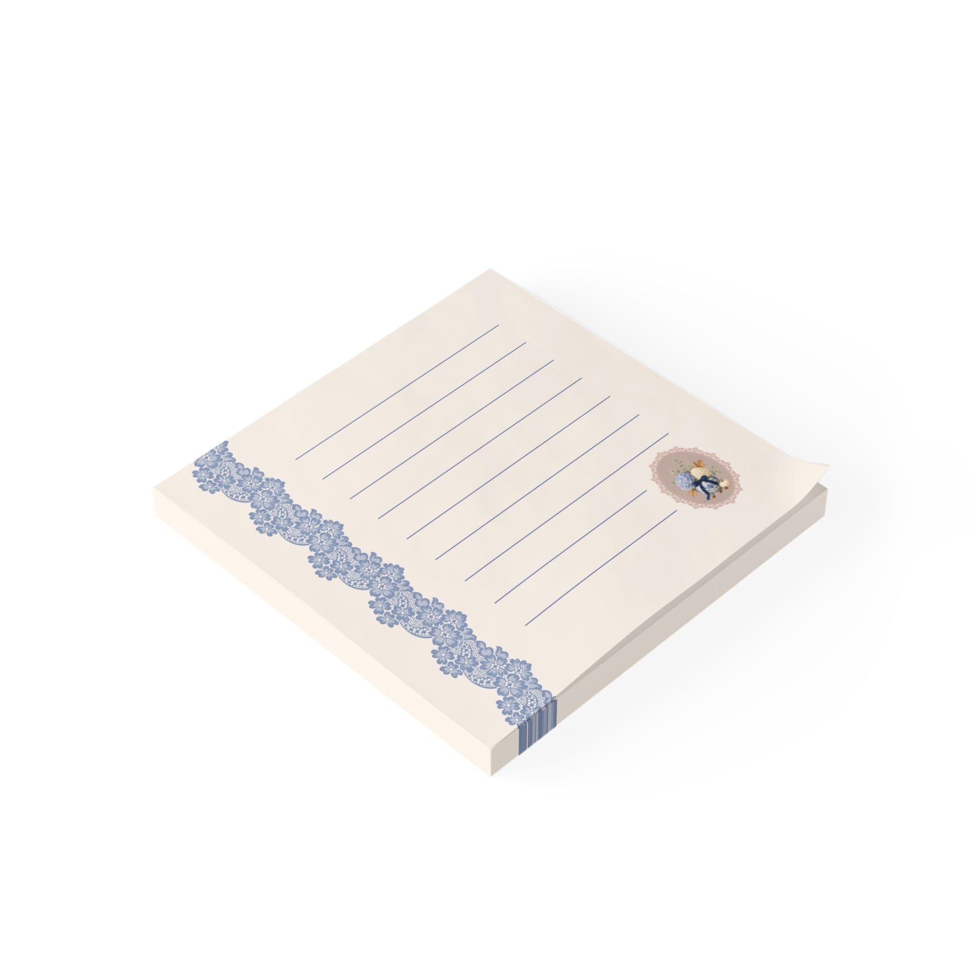 Angled view of the vintage floral sticky note pad featuring blue lace trim, lined writing pages, and a small botanical bouquet illustration.
